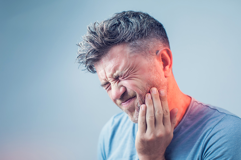 Man grabbing his jaw due to dental pain